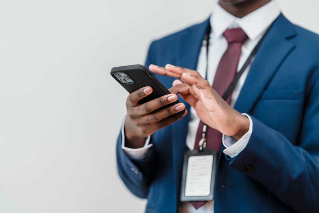 Processus d'Inscription A business professional in a suit using a smartphone indoors, focused on screen interaction.